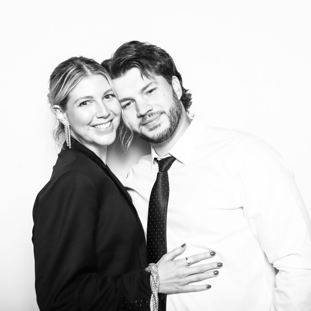 A couple using the photobooth from Elyon Images to take a glam black and white photo
